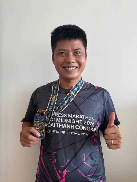 A finisher holding their X Challenge medal