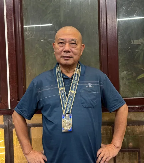 A finisher holding their X Challenge medal