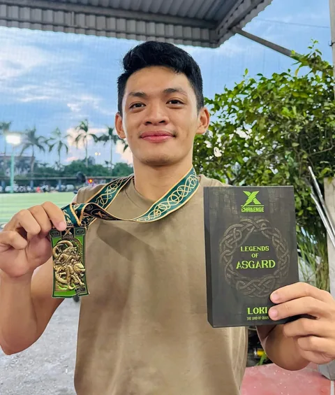 A finisher holding their X Challenge medal